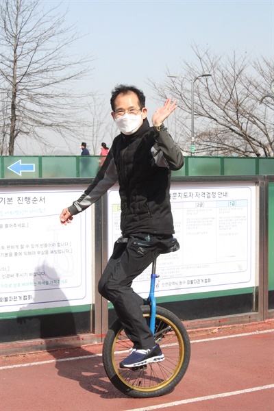  외발자전거 동호회 회원이 자전거를 타며 인사하고 있다.
