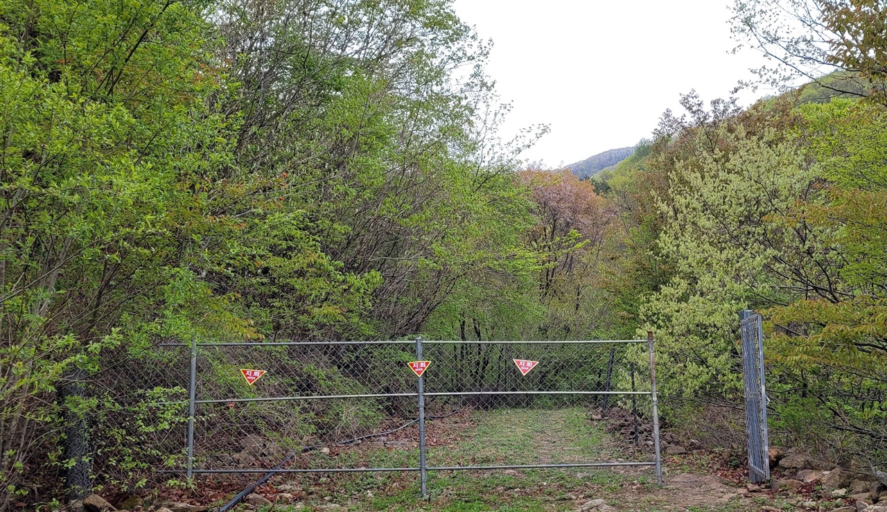 숲길체험지도사는 역삼각형 모양의 지레 표지판이 있는 철조망 옆 철조망 문으로 일행을 안내했다