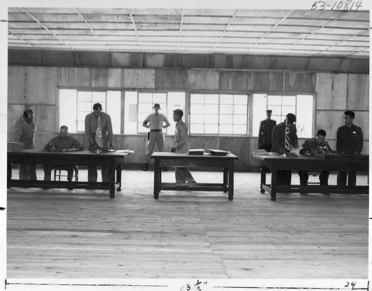 1953. 7. 27. 판문점, 정전회담 조인식. 왼쪽 책상에서는 유엔군 측 대표 해리슨 장군이, 오른쪽 책상에서는 북한 측 남일 장군이 서명하고 있다.