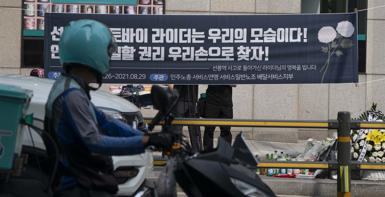 한 오토바이 배달원이 신호 대기 중 서울 강남구 선릉역 인근 보행로에 마련된 교통사고 사망 배달원의 추모공간을 바라보고 있다.
