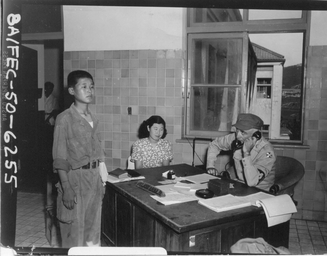 1950. 8. 18. 미8군 하사관 포로심문관(오른쪽)이 가장 나이 어른 북한 인민군 포로를 심문하고 있다(그의 이름은 김해심, 가운데 통역비서의 이름은 이수경이다).