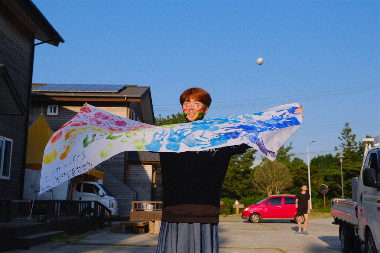 중3 김태형학생이 젠더리스룩을 입고 함께 만든 깃발을 펄럭이고 있다