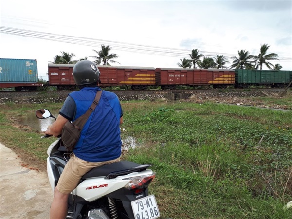 야자수 나무가 남쪽 나라 임을 말해주는, 베트남 나트랑 근교의 시골 마을. 화물을 실은 기차가 지나가기를 기다리고 있다.