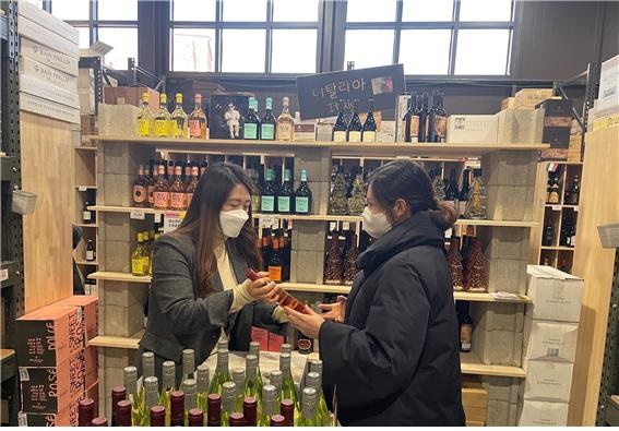 최소라씨(왼쪽)가 자신이 근무하는 대형 주류 매장에 방문한 고객에게 와인을 추천하고 있는 모습