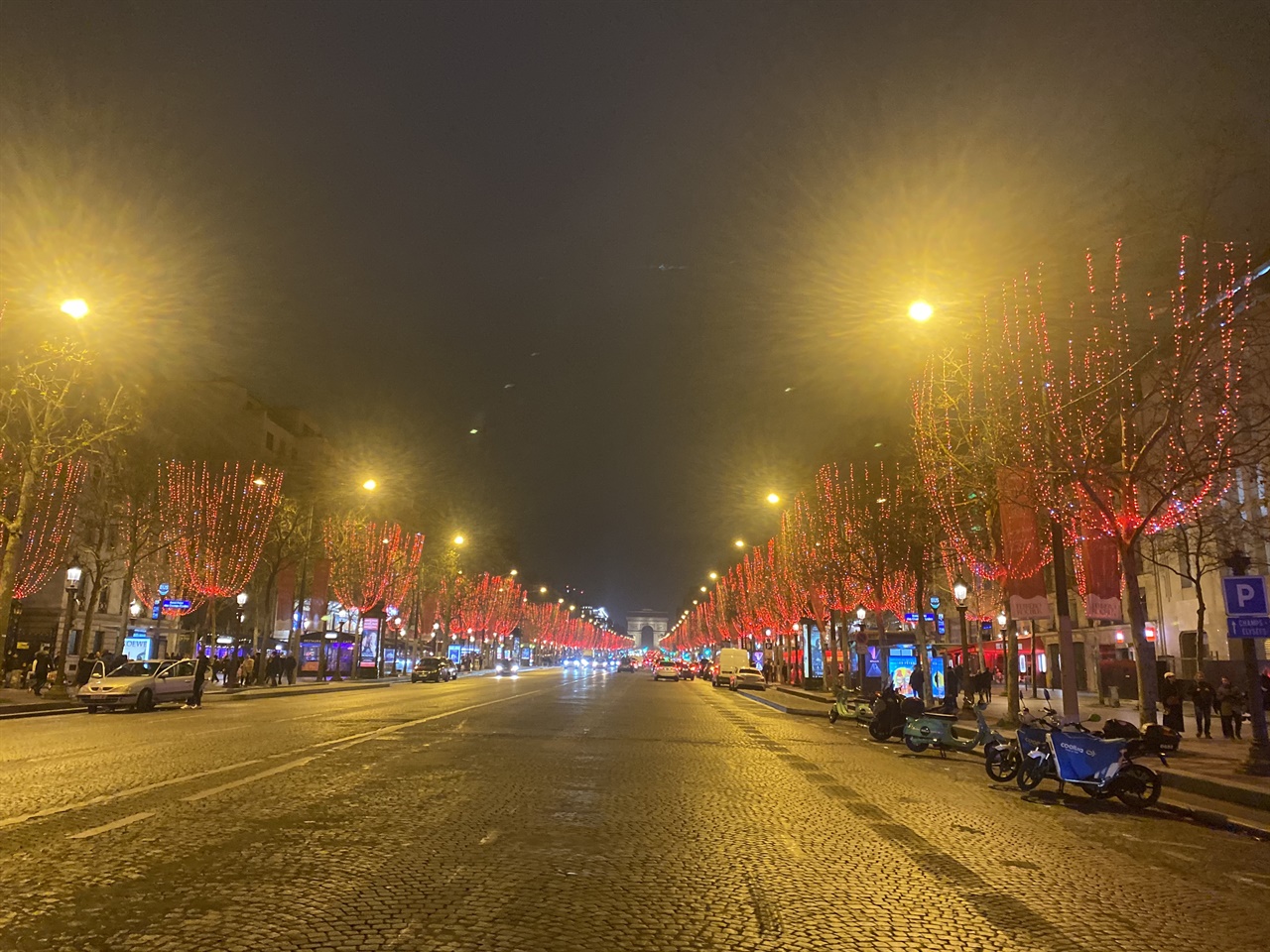 2021년 크리스마스 이브 저녁의 샹젤리제 거리 모습. 저 멀리 개선문이 보이고, 나무에 설치된 붉은 조명이 크리스마스 분위기를 내고 있다. 