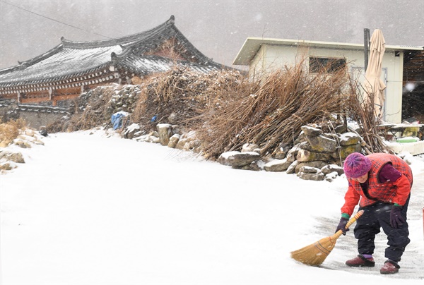1월 13일 경남 거창에 눈이 내리자 한 주민이 쓸어내고 있다.