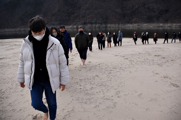 참여자들이 신발을 벗고 맨발로 모래의 감촉을 온몸으로 느끼며 걷고 있다. 