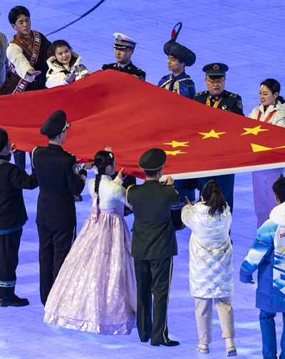 4일 오후 중국 베이징 국립경기장에서 열린 2022 베이징 동계올림픽 개회식에서 치마 저고리와 댕기 머리를 등 한복 복장을 한 공연자가 개최국 국기 게양을 위해 중국의 오성홍기를 옮기고 있다.