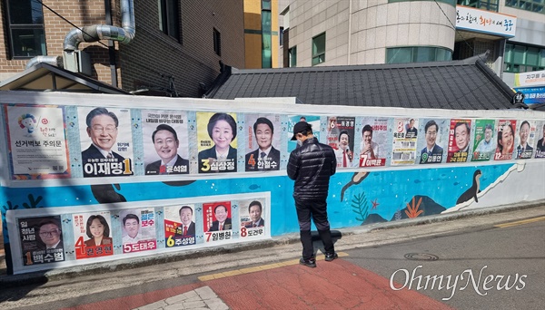 지난 5일 오후 대구 동인동행정복지센터 앞 담벼락에 붙어있는 대통령선거 후보 벽보를 한 시민이 유심히 바라보고 있다.