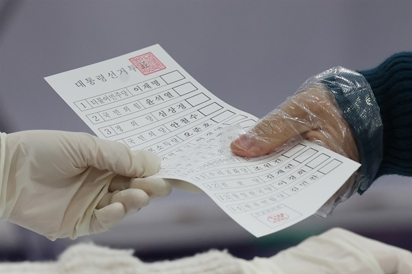 제20대 대통령선거일인 9일 오전 서울 강서구 현대태권도 체육관에 마련된 화곡8동 제5투표소에서 유권자가 투표용지를 받고 있다.