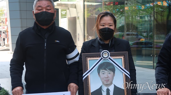 이동우씨의 유족들이 15일 동국제강 본사 앞에서 피켓과 영정사진을 들고 섰다.