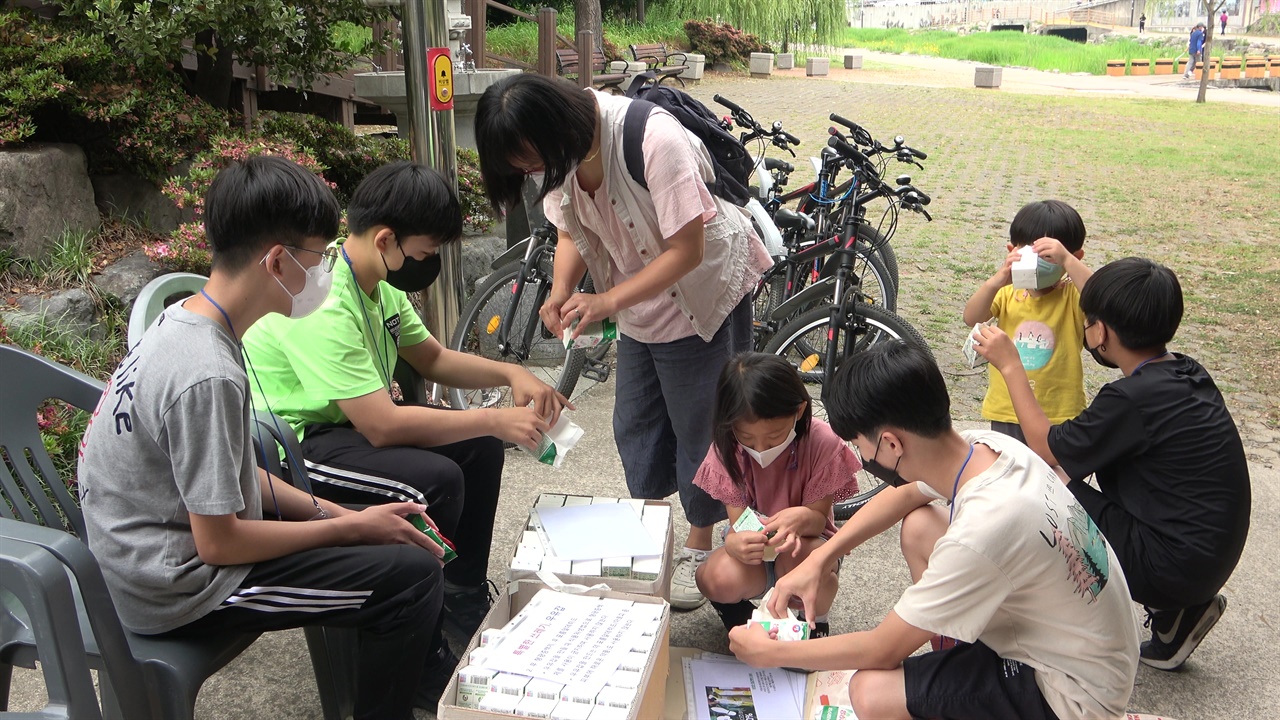 행사에 참여한 시민과 어린이에게 우유곽 재활용과 손으로 펴는 방법을 알려주는 순천삼산초등학교 6학년 학생들