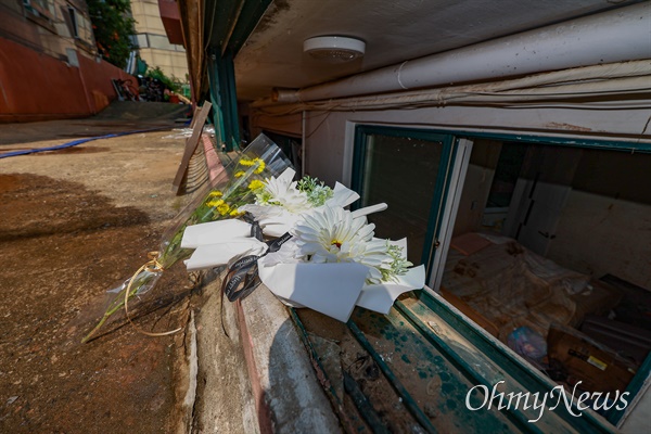 지난 12일 오후 서울 관악구 신림동 한 빌라의 뜯겨진 반지하 창틀에 침수된 반지하방에서 구출되지 못하고 숨진 3명을 추모하는 국화꽃이 놓여 있다.