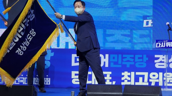 더불어민주당 경남도당 위원장에 선출된 김두관 의원이 당기를 흔들고 있다.