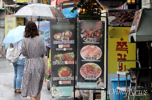 최근 물가의 고공행진으로 하루 한 푼도 쓰지 않는 ‘무지출 챌린지’가 청년세대에서 유행하고 있는 가운데, 25일 오후 서울 종로구 세종마을 음식문화 거리에서 한 시민이 음식 광고판 앞을 지나가고 있다.