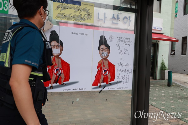 13일 오전 경찰이 삼각지파출소앞 버스정류장에 붙은 윤석열 대통령 부부 풍자 포스터를 뜯어내고 있다.