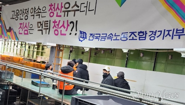 멈춰 선 생산 설비 앞에 삼삼오오 모여 있는 한국와이퍼 노동자들
