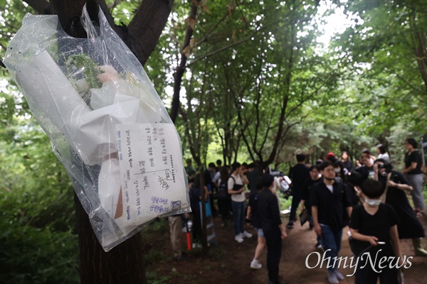 8월 24일 오전 서울 관악구 신림동 야산 등산로 성폭행 살인 사건 현장에 시민이 피해자를 추모하며 두고 간 편지와 꽃다발이 나무에 걸려 있다.