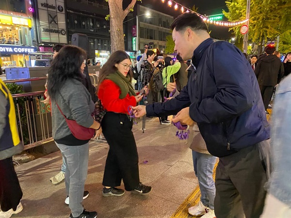 지난 10월 28일 토요일 밤 '10·29 이태원 참사 시민대책회의' 활동가들이 이태원에서 시민들에게 보라색 리본과 팔찌를 나눠주고 있다.