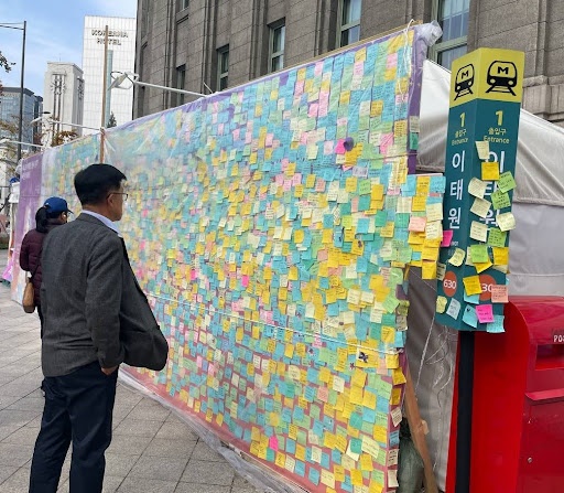 시민들이 서울광장 분향소에 설치된 10.29 이태원참사 추모의 벽에 빼곡히 붙은 메시지를 읽고 있다