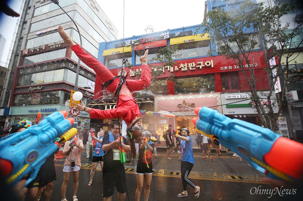  25일 오후 서울 서대문구 신촌 연세로에서 열린 '제3회 신촌 물총축제'에서 시민들이 물총을 쏘며 즐거운 시간을 보내고 있다. 대형크레인에 매달려 시민들과 물총싸움을 벌이던 연기자가 공중곡예를 선보이고 있다.