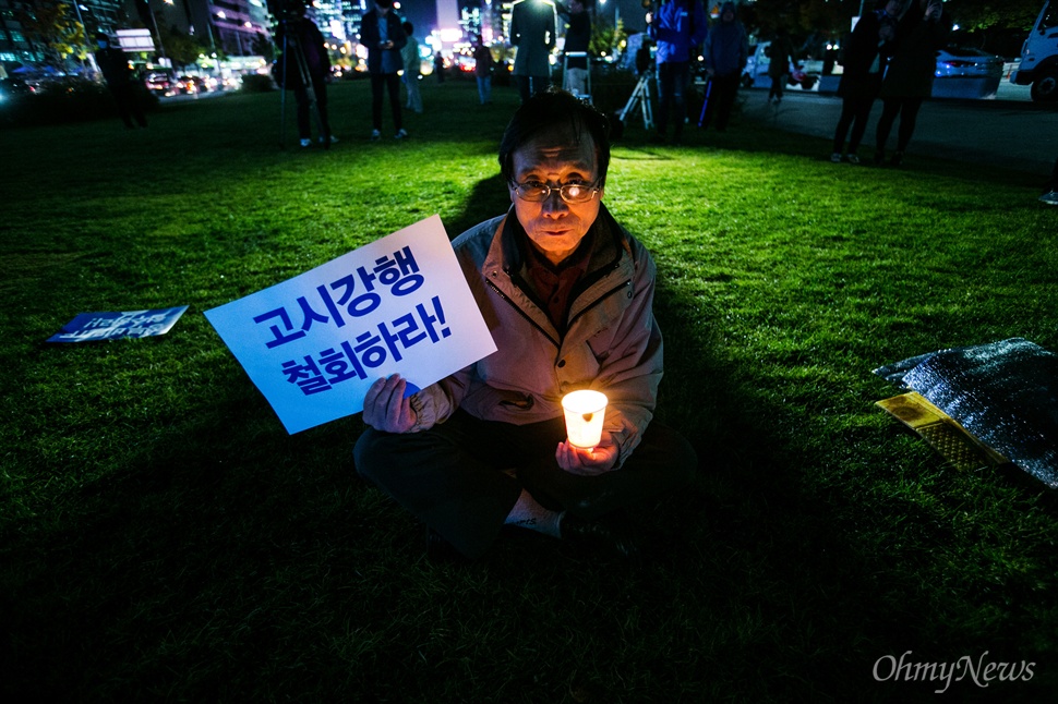  27일 오후 서울 광화문광장에서 역사교과서 국정화 반대 결의대회 및 시민사회 문화제에 참석한 한 시민이 촛불과 피켓을 들고 있다. 