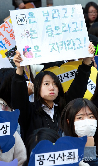 "눈은 보라고! 귀는 들으라고! 마음은 지키라고!" 28일 오후 서울 중화동 일본대사관앞에서 일본군위안부 문제 해결을 위한 1202차 수요집회가 초-중-고-대학생과 시민들이 참석한 가운데 열리고 있다. 한 학생이 일본대사관을 향해 "눈은 보라고! 귀는 들으라고! 마음은 지키라고!"가 적힌 손피켓을 들어보이고 있다.