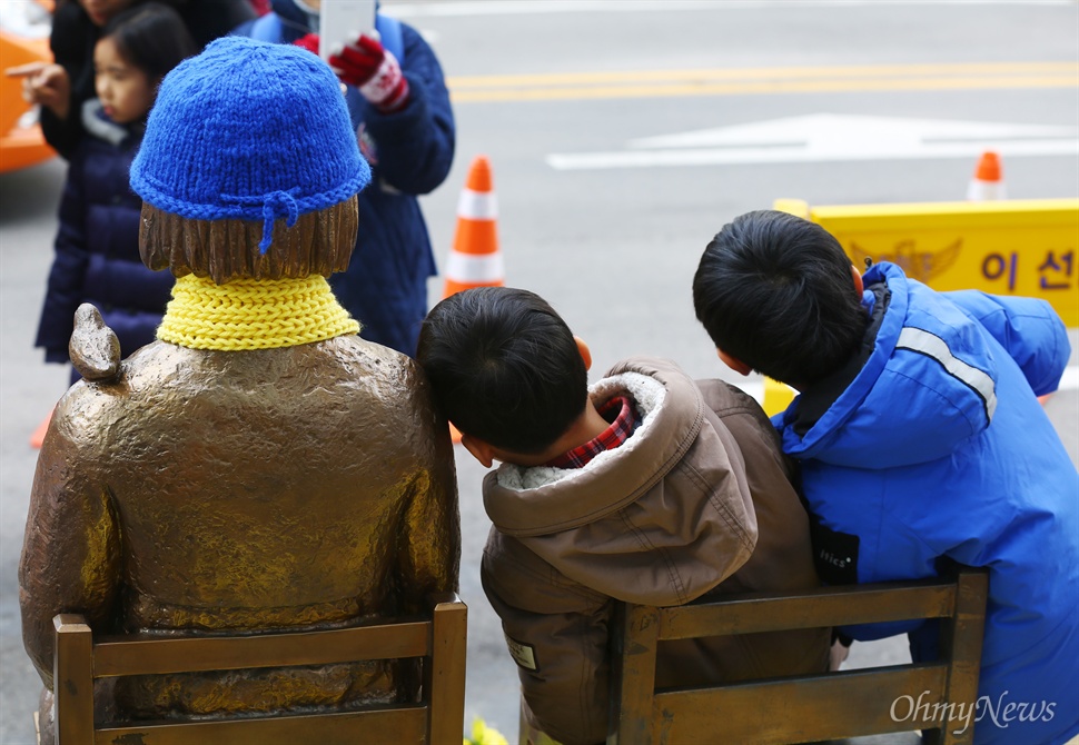 소녀상에 기댄 어린이 15일 오후 서울 종로구 일본대사관 앞 평화의 소녀상에 어린이들이 방문해 소녀상의 의미에 대해 설명을 듣고 함께 사진을 찍고 있다. 