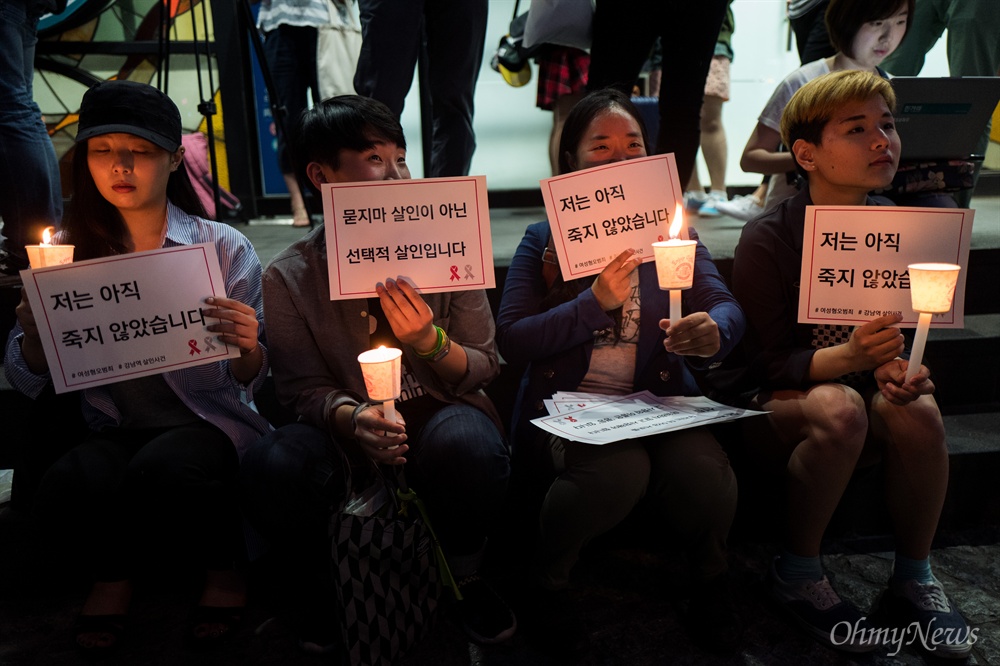 "저는 아직 살아 있습니다.  강남역여성살인사건이 발생한지 이틀이 지난 19일 오후 서울 강남역 10번 출구 인근에서 피해자를 추모하는 시민들이 손피켓과 촛불을 들고 있다. 