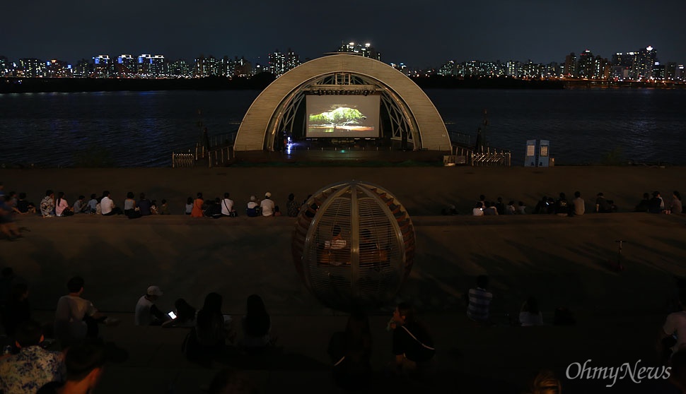  시민들이 12일 오후 서울 여의도 한강공원에서 열린 '서울밤도깨비야시장'을 찾아 무더위를 식히며 영화를 관람하고 있다.