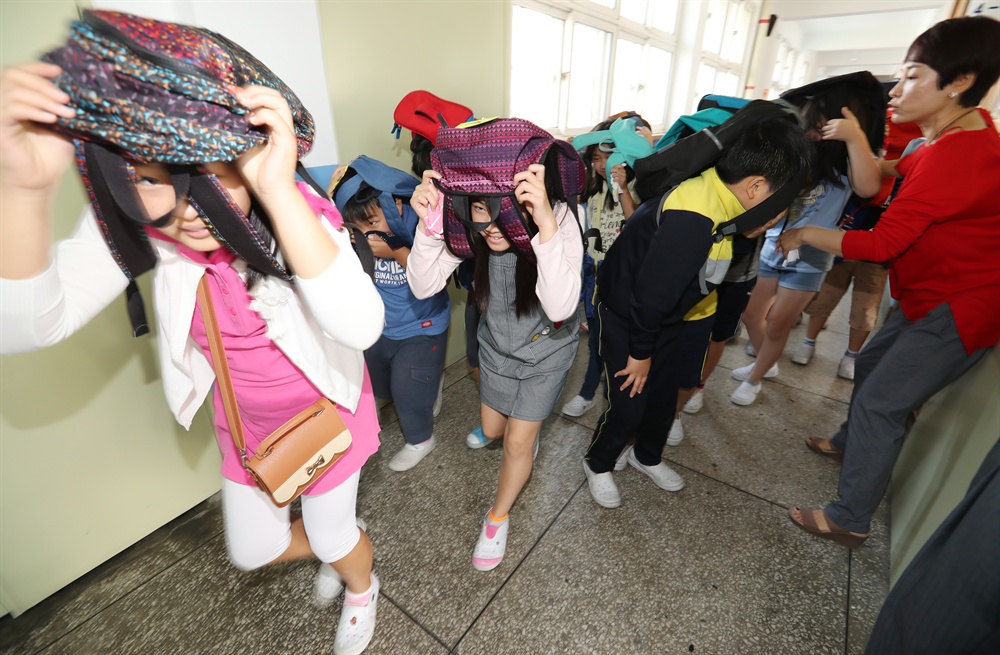 지진 대비 이젠 더 철저하게! 23일 오전 서울 강북구 송중초등학교에서 지진대피 훈련이 실시되고 있다. 지진경보가 울리자 학생들이 신속하게 가방으로 머리를 보호하며 대피하고 있다.