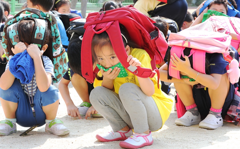 예사롭지 않은 초등생들 눈빛 23일 오전 서울 강북구 송중초등학교에서 지진대피 훈련이 실시되고 있다. 지진경보가 울리자 학생들이 신속하게 가방으로 머리를 보호하며 대피하고 있다.