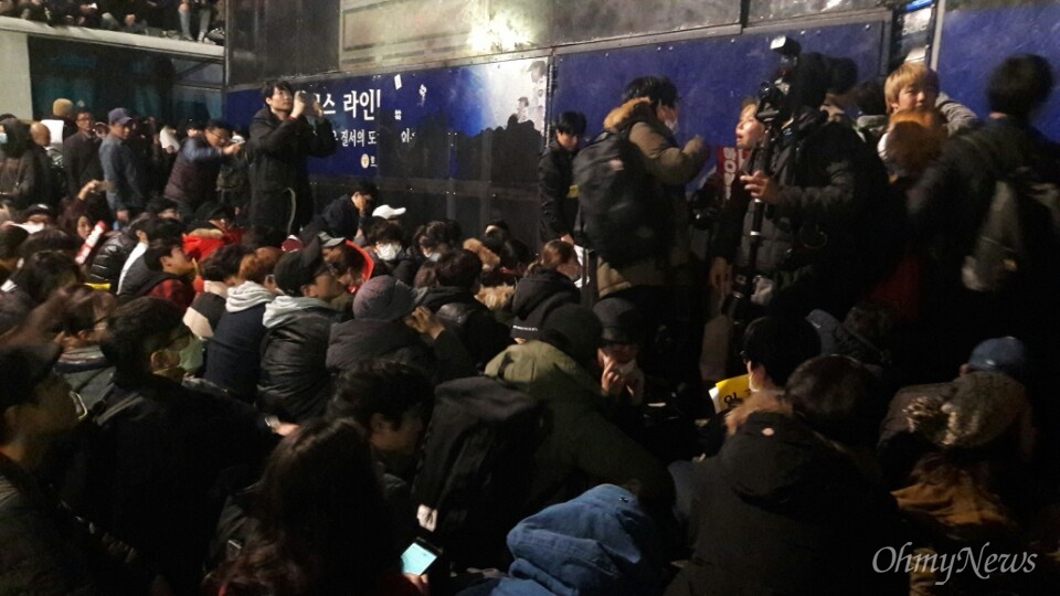  13일 새벽, 경복궁역 인근 차벽 앞 사람들이 자리에 앉고 있다.