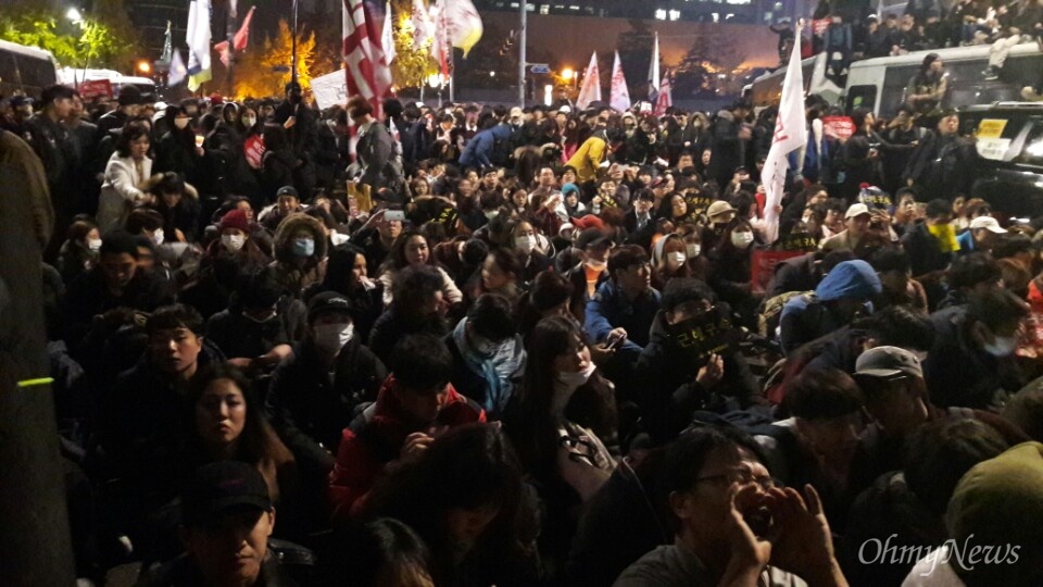  13일 새벽, 경복궁역 인근 차벽 앞 사람들이 자리에 앉고 있다.