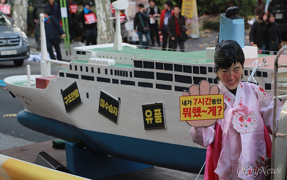  박근혜 대통령의 가면을 쓴 시민이 12일 오후 서울 종로구 대학로에서 세월호 모형을 실은 차량에 올라타 세월호참사 당시 박 대통령의 7시간 행적을 규탄하는 퍼포먼스를 벌이고 있다.