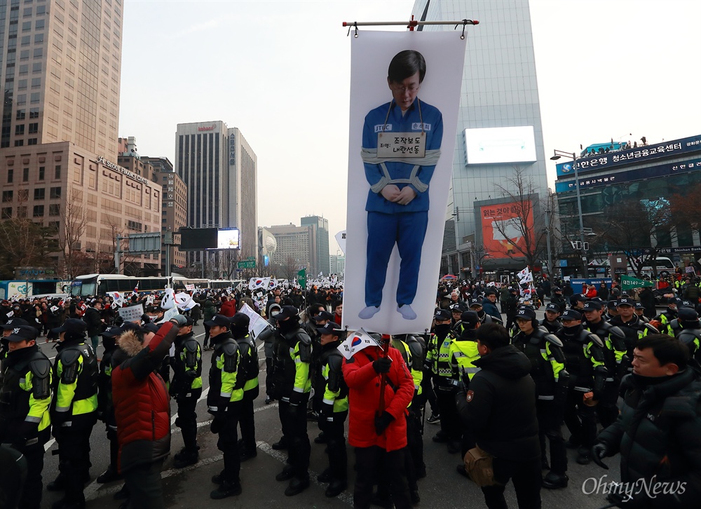 'JTBC 손석희' 비난하는 박근혜 지지자들 박근혜 대통령 지지자들이 24일 오후 서울 청계광장에서 탄핵반대 집회를 열고 있는 가운데, 비선실세 최순실의 태블릿PC를 입수하고 보도한 JTBC 손석희 사장이 포승줄에 묶인 사진이 등장했다.