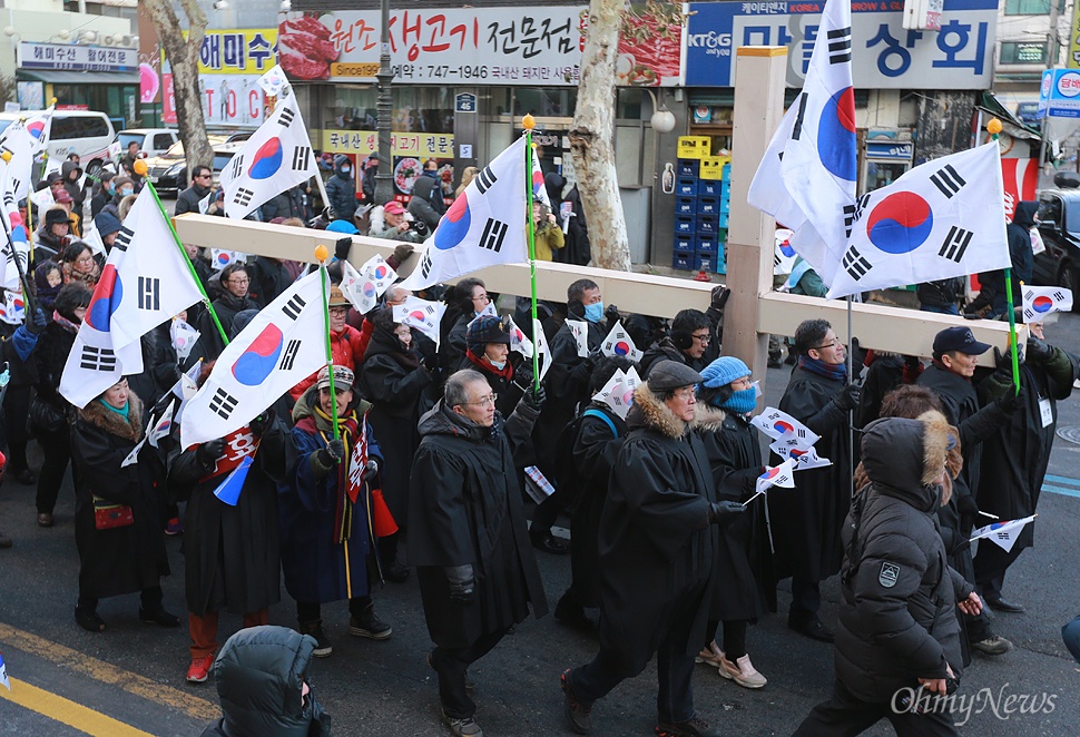 대형 십자가 메고 거리 행진하는 목회자 "박근혜 탄핵 무효" 14일 오후 서울 종로구 대학로에서 박사모 주축으로 구성된 '대통령 탄핵기각을 위한 국민총궐기운동본부' 주최로 열린 박근혜 대통령 탄핵반대 집회에 참석한 목회자들이 대형 십자가를 어깨에 메고 대통령 탄핵 기각을 요구하며 거리행진을 벌이고 있다.