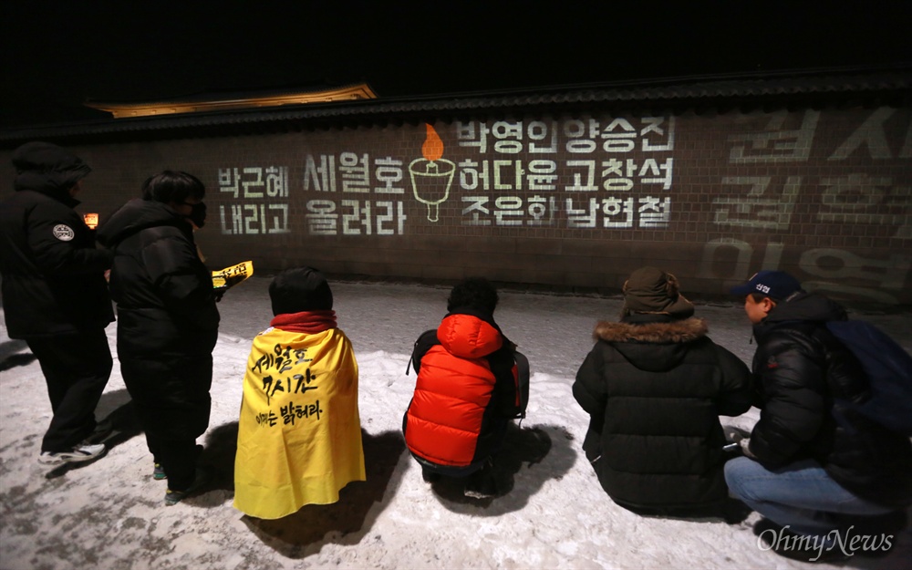 광화문 담벼락에 비춰진 세월호참사 미수습자 이름 21일 오후 서울 종로구 광화문광장에서 열린 '내려와 박근혜 바꾸자 헬조선 설맞이 촛불-13차 범국민행동의 날'에 참석한 시민들이 세월호 미수습자의 이름을 레이저 불빛으로 광화문 담벼락에 비추며 세월호참사 진상규명을 촉구하고 있다.