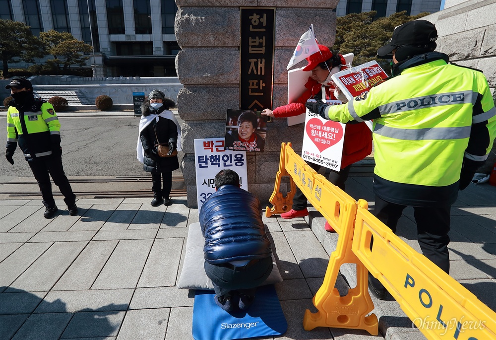 '탄핵인용 33배' 방해하는 박 대통령 지지자  24일 오후 서울시 종로구 재동 헌법재판소앞에서 한 시민이 박근혜 대통령 탄핵인용 촉구 ’릴레이 33배’를 하는 가운데, 박 대통령 지지자가 ‘박 대통령 사진을 향해 절을 하라’며 사진을 내밀어 방해하고 있다.