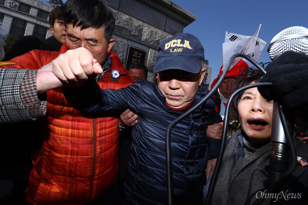  헌법재판소의 박근혜 대통령 탄핵심판 선고기일 발표가 예상되는 8일 오전 서울 종로구 헌법재판소 앞에서 대통령 측 대리인단 김평우 변호사가 기자회견을 하기 위해 친박단체 회원들의 보호를 받으며 이동하고 있다.