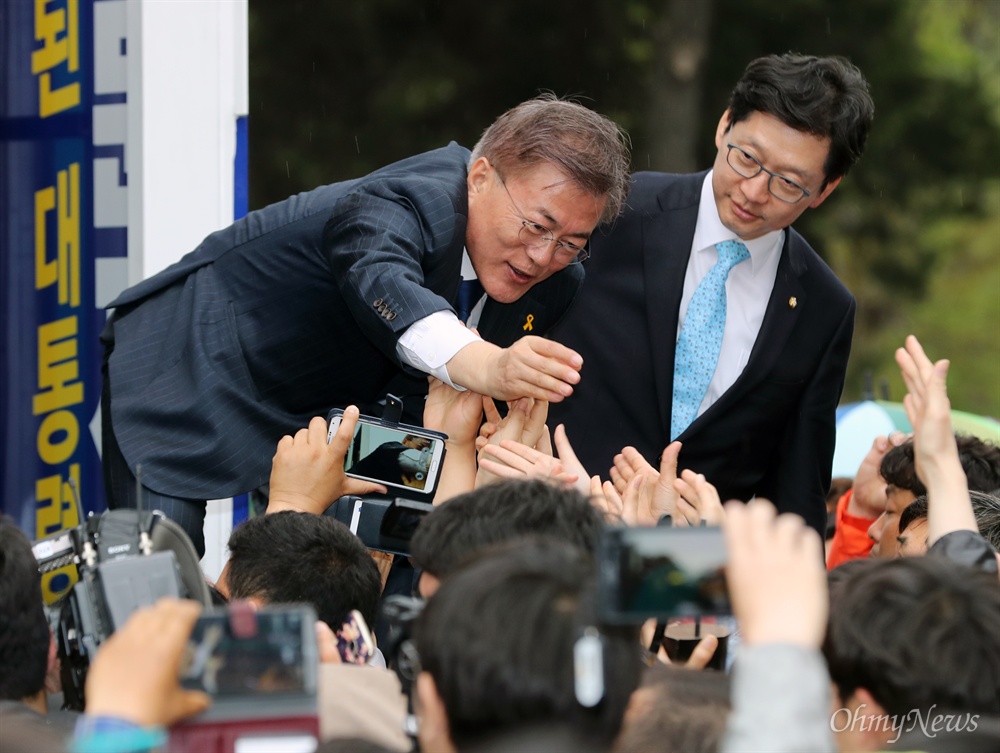  더불어민주당 문재인 대선후보가 18일 오후 전주 전북대 입구 거리유세에서 손을 뻗는 시민들의 손을 잡고 있다. 오른쪽은 김경수 대변인.