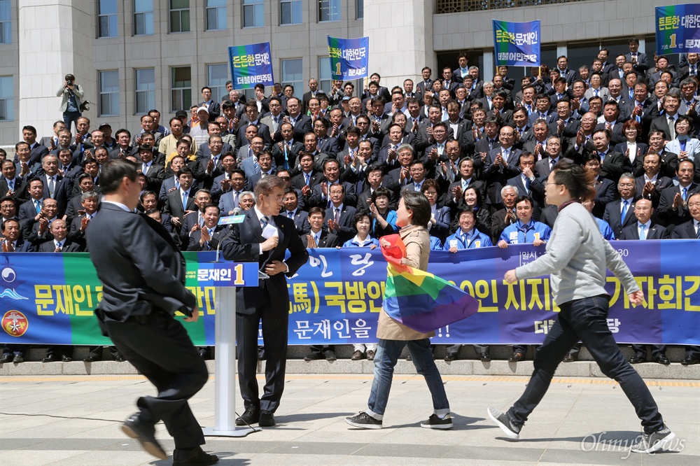 '동성애 반대' 문재인 사과 촉구한 성소수자 기습시위 문재인 더불어민주당 대선후보가 26일 오전 국회 본관 앞 계단에서 열린 ‘천군만마(千軍萬馬) 국방안보 1000인 지지선언’ 기자회견에서 인사말을 마친 직후 성소수자 단체로부터 거센 항의를 받고 있다. 레인보우 깃발을 들고 문 후보를 향해 기습시위를 벌인 이들은 전날 TV토론에서 "동성애 반대 뜻을 밝힌 것에 대해 문 후보의 사과를 촉구했다. 
