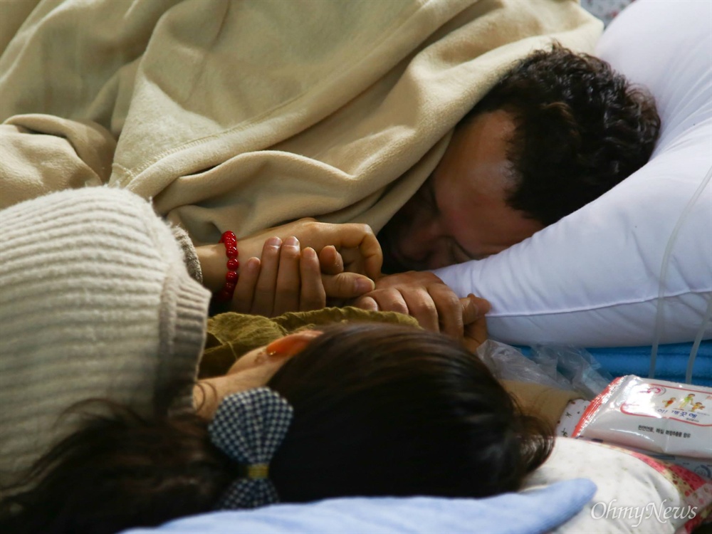  세월호 미수습자 남현철군의 아빠와 엄마가 2014년 4월 17일 진도체육관에서 쓰러져 링거를 맞으며 손을 꼭잡고 있다. 