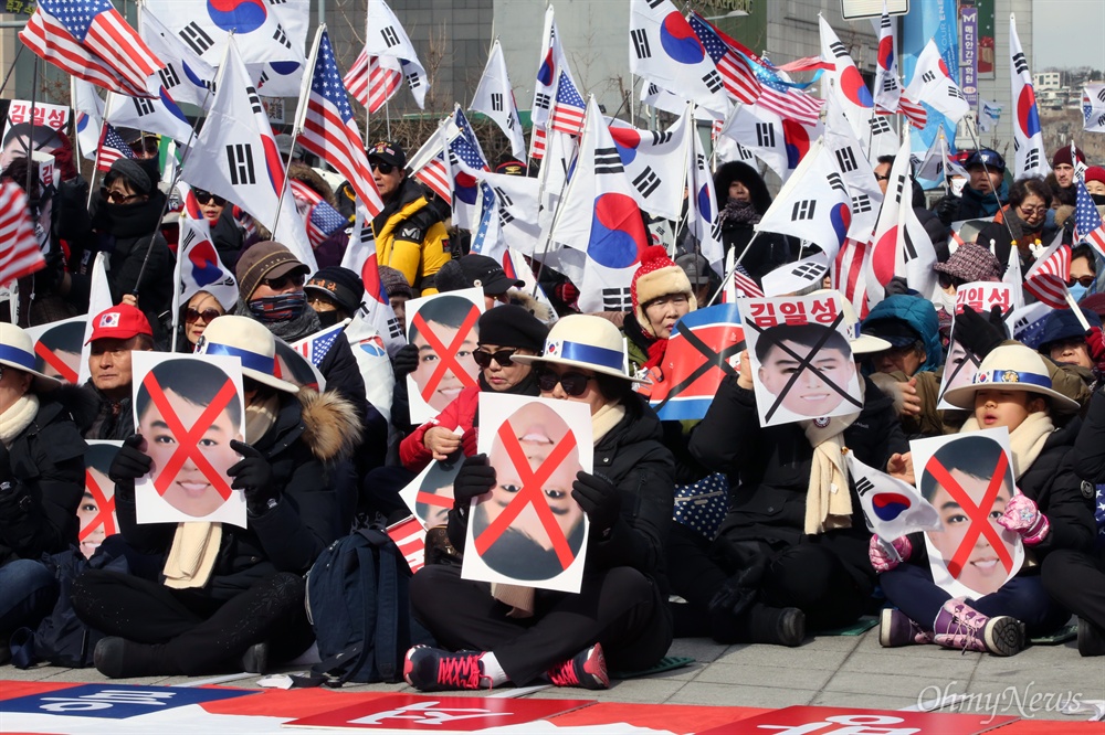 평양올림픽 반대 집회에 등장한 '김일성 가면 소동' 사진  11일 오후 서울 동대문디자인플라자 광장에서 열린 '평양올림픽' 반대 집회 참가자들이 '김일성 가면 소동'을 일으킨 사진을 들고 있다. 