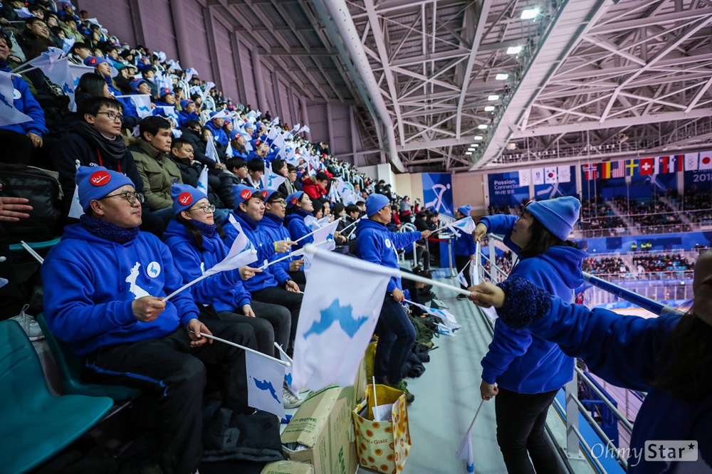  12일 오후 강원도 강릉 관동아이스하키센터에서 남-북 단일 여자하키 대 스웨덴 경기가 펼쳐지는 가운데 남측응원단이 파란색 옷을 입고 한반도기를 이용해 응원을 하고 있다.