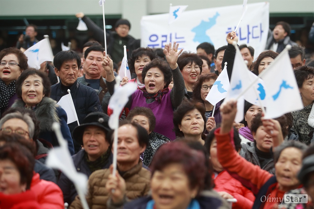 북측 응원단 반기는 시민들 "조국 통일" 북측 응원단과 취주악단이 23일 오후 강원도 인제군 다목적구장을 방문해 2018 평창동계올림픽 성공 개최 기원 공연을 선보이자, 시민들이 한반도기를 흔들며 환호하고 있다.