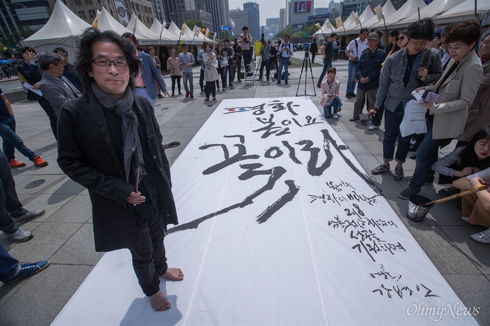  캘리그라피스트 강병인 작가가 26일 오후 서울 광화문 광장에서 남북정상회담 성공을 기원 하는 대형 붓글씨를 쓰고 있다. 강 작가는 한지 위에 ‘평화 봄이요 꽃이라’고 쓰고 마지막 두 개의 획을 시민이 참여해 찍어 완성했다.