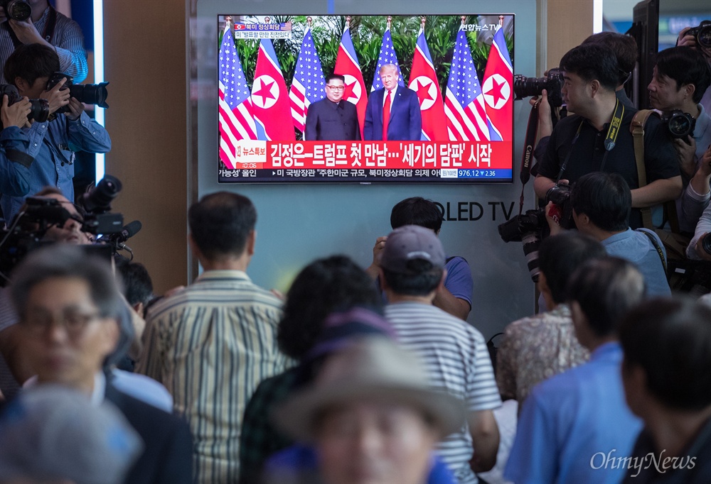  북미정상회담이 열린 12일 오전 서울역 대합실에서 취재진들이 김정은 국무위원장과 트럼프 미 대통령의 만남을 지켜보는 시민들을 취재하고 있다.