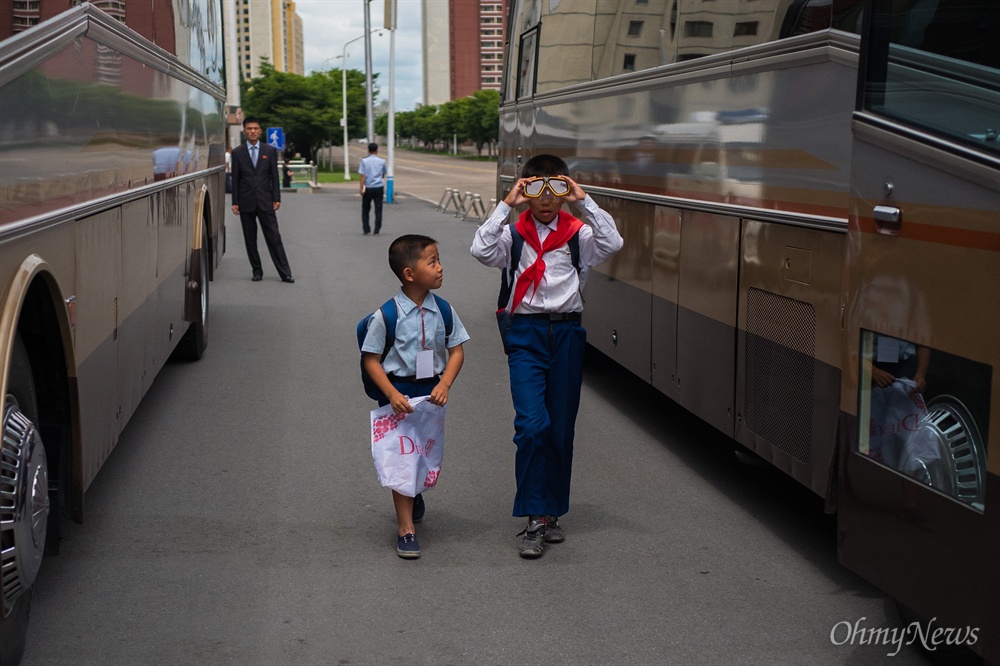  5일 오전 평양 고려호텔 앞에서 길을 가며 물안경을 써보는 학생과 그 모습을 바라보는 어린이의 모습 뒤로 북측 안내원의 모습이 보이고 있다.