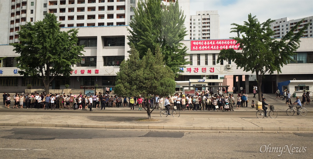  6일 오후 평양 시내 고층 건물 앞 정류장에 주민들이 대중교통을 이용하기 위해 줄지어 서있다.
